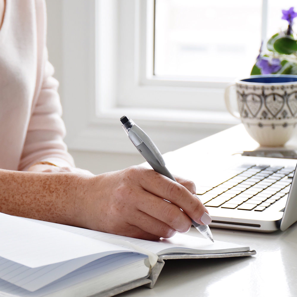 Woman writing in journal and a keyboard